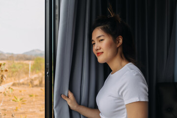 Close up of asian woman open the curtain and look out to the view.