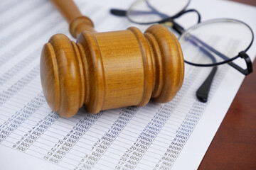 Close-up of judge gavel, eyeglasses and financial document on table. Audit and financial fraud...