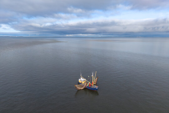 Aerial of fishing ship, boat trawling nets with gulls at Wadden sea