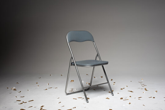 Photo studio with white background in the middle there is a grey chair. Festive confetti lies on the floor.
