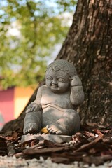 Obraz premium Stone statue of a smiling baby by a tree