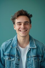 Fototapeta premium A person wearing a denim jacket smiles at the camera, looking friendly and approachable