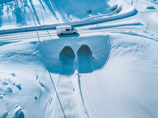 Aerial drone view of snow covered road with cargo car and snowmobile in winter Finland, Lapland