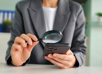 Businesswoman using smartphone with magnifying glass