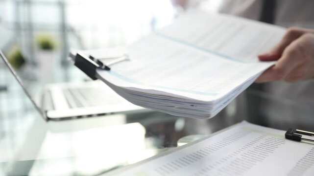 A man is writing on a piece of paper with a pen on a laptop