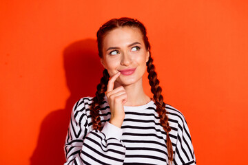 Fototapeta premium Charming young woman in striped pullover with playful expression against vibrant orange background