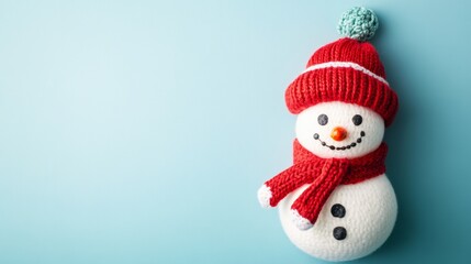 Fototapeta premium Festive child's handmade snowman craft with colorful scarf and hat on a light blue background for winter creativity