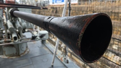 Long black metal barrel of WWII naval machinegun cannon mounted on the deck of a ship