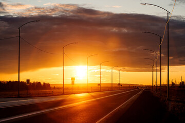 An empty road into a bright orange sunset