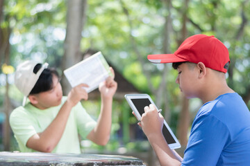 Asian schoolboys are studying high level of trees in school botanical garden by using inclinometer...
