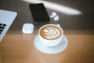 A cup of coffee is placed near a laptop on a table with space for copying documents, suggesting a break from work or a relaxing time at a cafe.