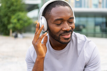 Music song concept. Good start day. Happy African American man listening modern hit on street in...