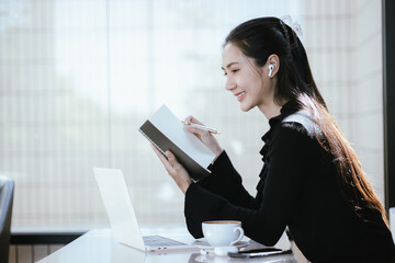 Young Asian woman taking a break, having a quiet time enjoying a cup of coffee and reading book in cafe