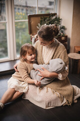 Happy mother and daughter and newborn  hugs near christmas decorated tree. beige and golden new year decorations, bokeh and pine wreath. 