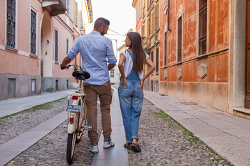 young smiling couple in love riding bicycles through the streets of a historic city