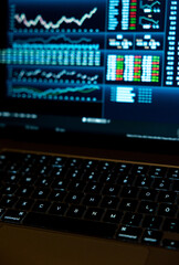 Close up notebook keyboard, blurred screen with stock market data. Stock market trading ...