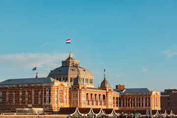 Naklejka premium Kurhaus in Scheveningen during sunset. The Dutch flag on top of the building.