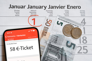 Auf einem Kalenderblatt vom Januar 2025, auf dem der 1. Januar mit einem Stift rot eingekreist ist, befindet sich ein Smartphone mit geöffneter Ticket-App mit einem 58-Euro-Ticket und 58-Euro-Bargeld