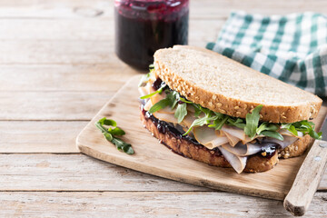 Turkey sandwich with cranberry sauce for Thanksgiving on wooden table. Copy space