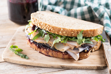 Turkey sandwich with cranberry sauce for Thanksgiving on wooden table