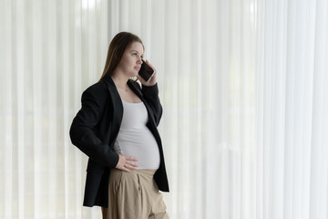 White pregnant woman talking on the phone. Pregnant businesswoman talking on the phone while working.