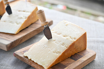 a piece of 30-month-aged Parmigiano Reggiano on a wooden cutting board with a knife made specifically for cutting it