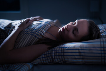 Sleeping woman in bed at night. Good dream after melatonin. Deep REM. Girl in dark bedroom. Pillow...