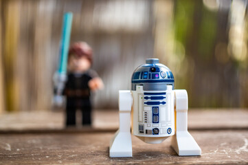 Fototapeta premium Lego Star Wars R2 D2 toy robot on the foreground and a Skywalker with blue laser sword