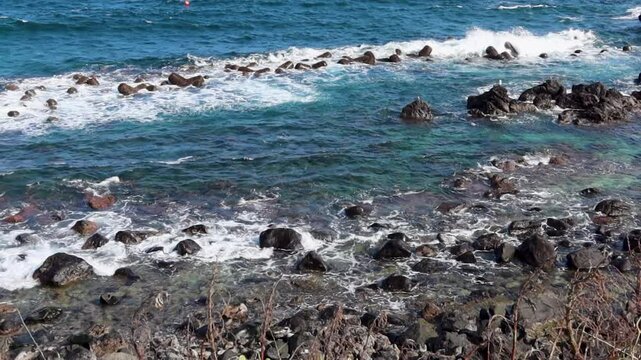 Natural rocks and artificial breakwaters block the waves.