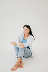 Fototapeta premium A woman in a white shirt and jeans showing a stylish and understated look. The light background and natural pose give the shot a modern feel.