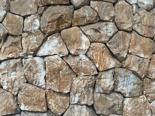 A close-up view of a textured stone wall with an intricate arrangement of natural-looking stones. 