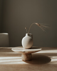 Still life composition featuring a classic milk or water jug and a wheat stem arranged on a neutral background. 