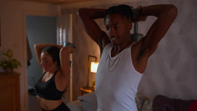 Black man smiles while exercising at home with wife