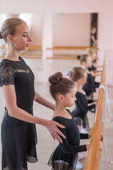 Caucasian woman teaches little girls ballet at the barre. Vertical photo. 