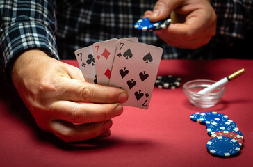 Playing cards in the hand of a gambler with a successful combination of three of a kind or set. A lucky win and chips on the table in a casino