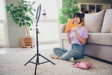Photo of pretty cheerful lady wear striped violet t-shirt showing pomade recording video modern device indoors room home house