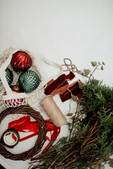 Materials for creating Christmas decor: vintage balls, twigs, wooden base for a wreath, velvet ribbons. Top view, space for text