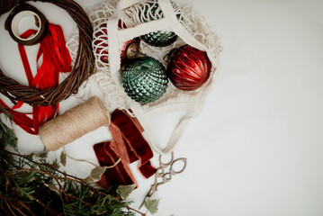 Durable and ecological materials for creating Christmas decor: vintage balls, twigs, wooden base for a wreath, velvet ribbons. Top view, space for text
