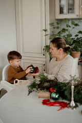Grandmother and grandson make Christmas decorations at a white table in the kitchen. Eco friendly handmade. Time together