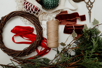 Durable and ecological materials for creating Christmas decor: vintage balls, twigs, wooden base for a wreath, velvet ribbons. Flatlay, top view