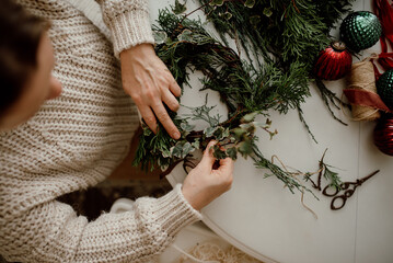 A woman makes a Christmas wreath from conifer branches from her own garden. Ecological hand-made decor. Top view