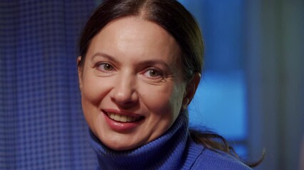 Adult 44 year old woman having lively conversation sitting at table in living room. Woman tells an emotional story, smiling.