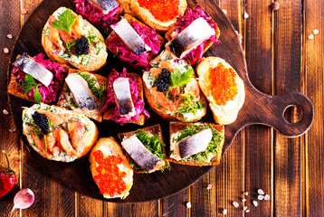 Cocktail canapes with herring, cream cheese and caviar on rye bread
