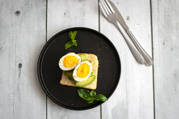 
Sandwiches with avocado, tomatoes and poached eggs. on a wooden backyard. Snidanok.