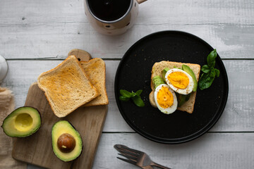 
Sandwiches with avocado, tomatoes and poached eggs. on a wooden backyard. Snidanok.