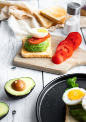 
Sandwiches with avocado, tomatoes and poached eggs. on a wooden backyard. Snidanok.