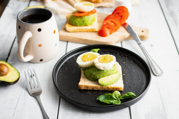 
Sandwiches with avocado, tomatoes and poached eggs. on a wooden backyard. Snidanok.