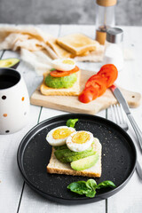 
Sandwiches with avocado, tomatoes and poached eggs. on a wooden backyard. Snidanok.