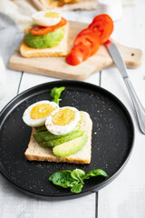 
Sandwiches with avocado, tomatoes and poached eggs. on a wooden backyard. Snidanok.