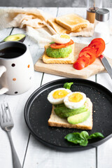 
Sandwiches with avocado, tomatoes and poached eggs. on a wooden backyard. Snidanok.
